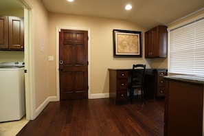 A kitchen with wooden cabinets, a white refrigerator, a wooden desk, and a framed map on the wall. - Incredible Estate 5 Bedrooms 3 Bathroom W/resort Style Rock Pool & Jacuzzi (Fullerton)