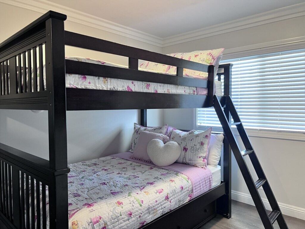 A bunk bed with a ladder, floral bedding, and a heart-shaped pillow.