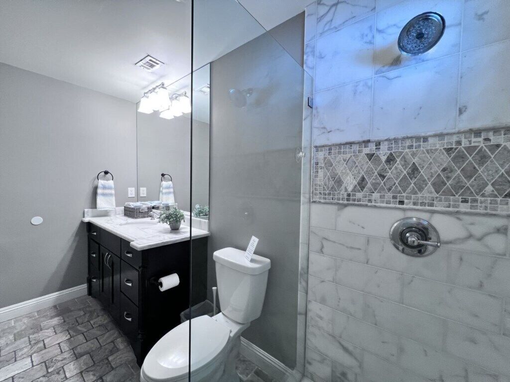 Un ba ño con inodoro, lavamanos, espejo y zona de ducha.
