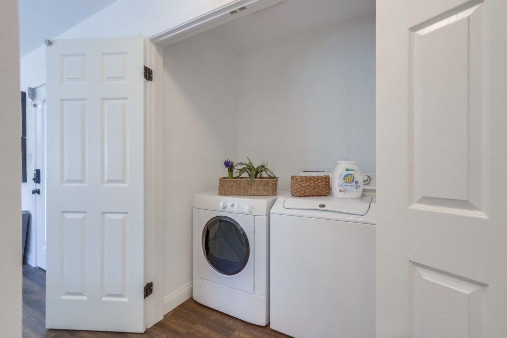 A laundry room with a washing machine, dryer, and baskets on the wall.