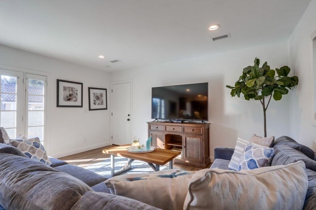 A living room with a sofa, a coffee table, a TV, and a plant.