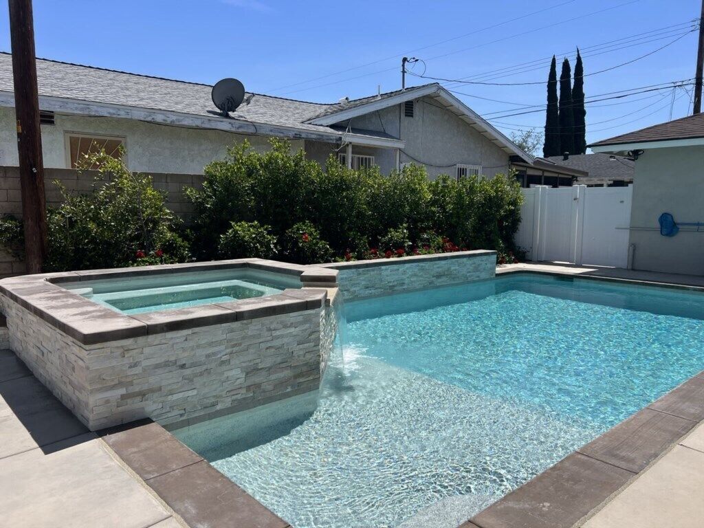 A rectangular swimming pool with stone walls and a clear blue water surface.
