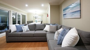A modern living room with a sectional sofa, a chandelier, and a painting on the wall. - 5 Bedroom 4 Bath Pool Home Near Disney (Anaheim)
