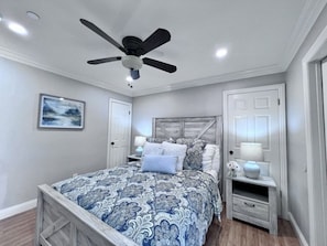 A bedroom with a bed, a ceiling fan, a nightstand, a dresser, and a door. - 5 Bedroom 4 Bath Pool Home Near Disney (Anaheim)