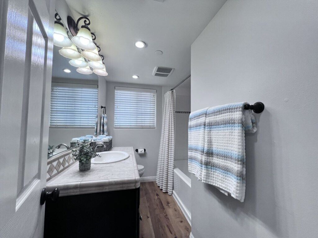 A bathroom with a sink, mirror, towel rack, and a shower curtain.