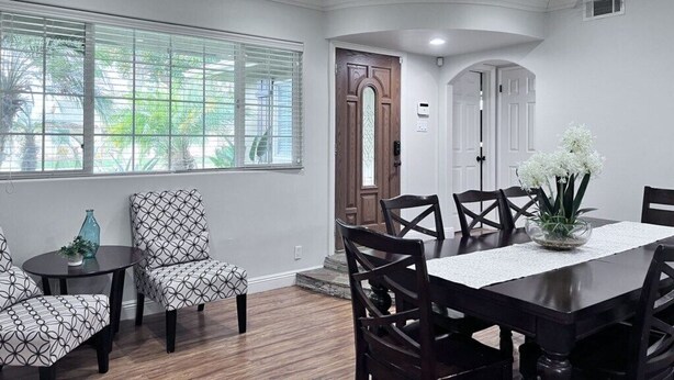 A dining area with a table and chairs, a window with blinds, and a door. - Lovely Anaheim Pool Home 1 Mile to Disney (Anaheim)