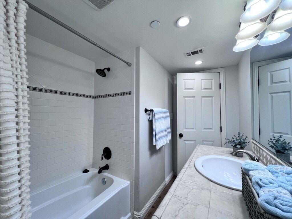 A bathroom with a bathtub, a sink, and a shower area.