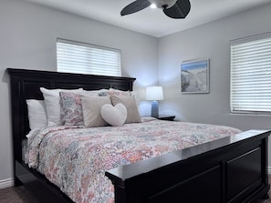 A bedroom with a dark wood bed, a floral bedspread, a nightstand with a lamp, and a framed picture on the wall. - Lovely Anaheim Pool Home 1 Mile to Disney (Anaheim)