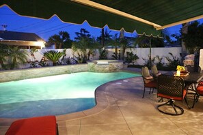A swimming pool with a curved edge, outdoor seating, and a covered patio area. - Snazzy 6 Bedroom 3 Bath Pool Home 1/2 Mile Walk to Disney (Anaheim)