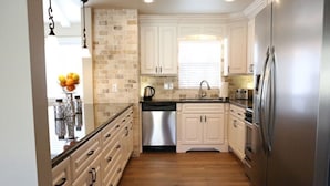 A kitchen with white cabinets, a stainless steel refrigerator, and a dishwasher. - Snazzy 6 Bedroom 3 Bath Pool Home 1/2 Mile Walk to Disney (Anaheim)