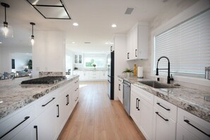 A modern kitchen with white cabinets, granite countertops, and a central island. - Awesome 5 Bedroom 3 Bath Pool Home With In-ground Jacuzzi (Orange)