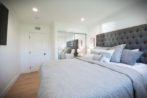 Une chambre à coucher avec un grand lit, une armoire, un miroir et une porte.