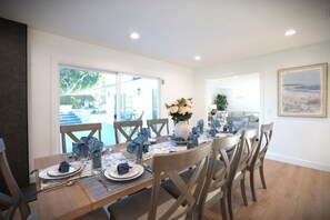 A dining area with a table set for four, chairs, a vase with flowers, and a painting on the wall. - Awesome 5 Bedroom 3 Bath Pool Home With In-ground Jacuzzi (Orange)