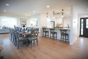 A modern kitchen with a central island, dining area with chairs, and a living room with a sofa.
