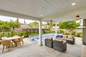 An outdoor patio with a hot tub, wicker furniture, and a view of the backyard. - Gorgeous Upgraded 5 Bedroom & 4 Bath Home With Jacuzzi (Orange)