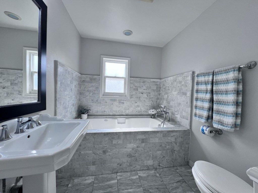 A bathroom with a white sink, a bathtub, and a toilet.