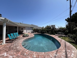 A swimming pool with a brick deck, surrounded by outdoor furniture and a covered patio area. - Anaheim California, Beautiful Pool Home, Short Walk to Disney (Anaheim)