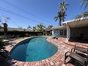 A swimming pool with a brick border, surrounded by palm trees and a patio area with chairs. - Anaheim California, Beautiful Pool Home, Short Walk to Disney (Anaheim)