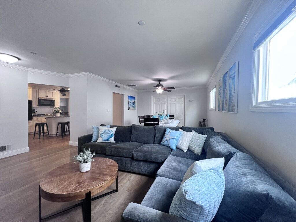 A modern living room with a sectional sofa, a round coffee table, and a ceiling fan.