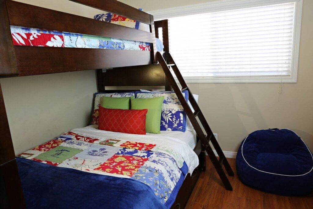 A bunk bed with a quilt, pillows, and a ladder.