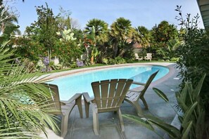 A swimming pool with two Adirondack chairs, surrounded by tropical plants and trees. - Comfy Pool Home,1/4 Mile Walk To Disneyland (Anaheim)