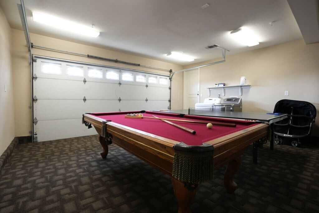 Une table de billard recouverte d’un drap de feutre rouge, une queue de billard et une bille.