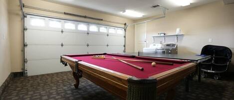 A pool table with a red felt surface, a cue stick, and a billiard ball.