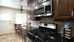 A kitchen with a stove, microwave, and cabinets. - Comfy Pool Home,1/4 Mile Walk To Disneyland (Anaheim)
