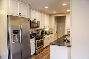 A modern kitchen with stainless steel appliances, white cabinetry, and a granite countertop. - Wonderful 4 Bedroom 3 Bath Pool Home 3/4 Mile To Disney (Anaheim)