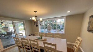 A dining area with a table and chairs, a chandelier, and a view through large windows. - Wonderful 4 Bedroom 3 Bath Pool Home 3/4 Mile To Disney (Anaheim)