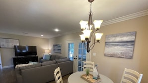 A living room with a sofa, a dining table with chairs, a chandelier, and a television. - Wonderful 4 Bedroom 3 Bath Pool Home 3/4 Mile To Disney (Anaheim)