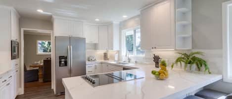 A modern kitchen with white cabinetry, a central island, and a built-in oven.