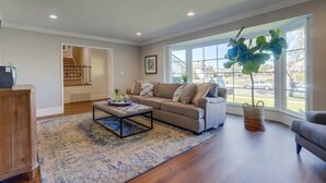 A living room with a sofa, ottoman, and a large window with a view.