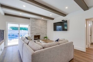 Una sala de estar con un sofá modular, una chimenea, un televisor de pantalla plana y un ventanal grande.