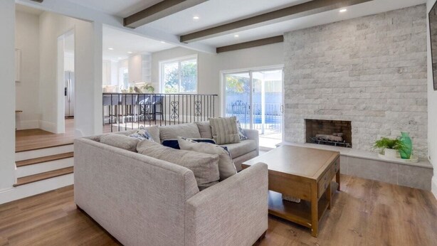 A spacious living room with a sofa set, a wooden coffee table, and a fireplace.