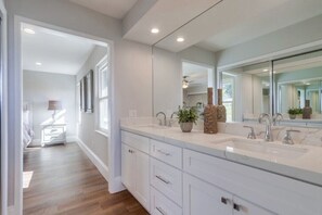 Un baño moderno con dos lavamanos, un espejo grande y una planta en maceta.