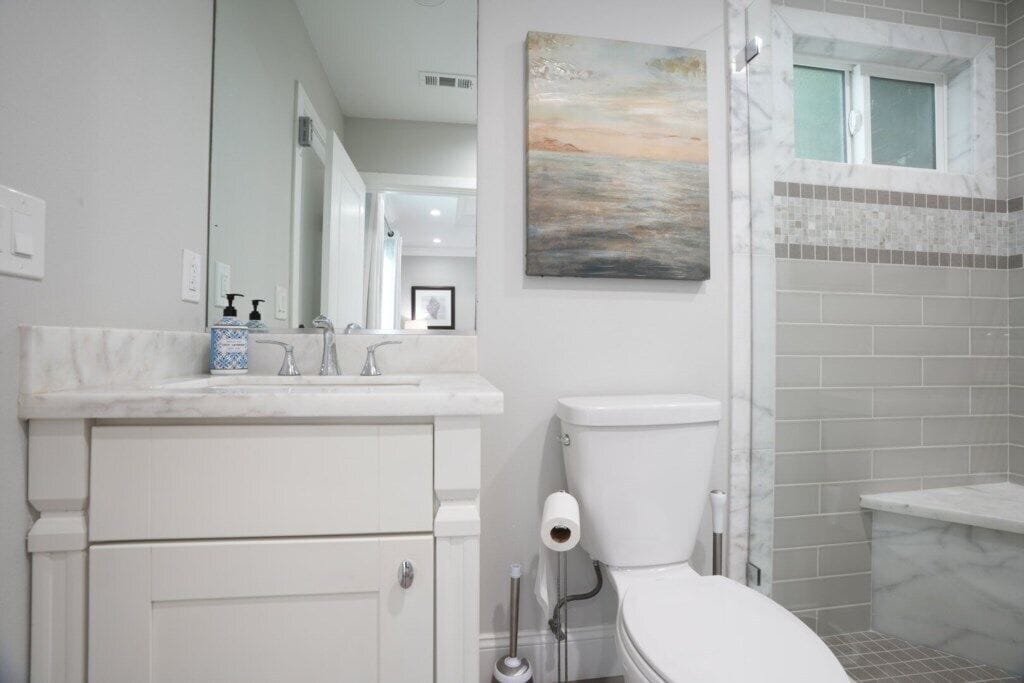 A bathroom with a toilet, sink, and mirror.