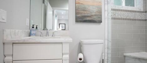 A bathroom with a toilet, sink, and mirror.