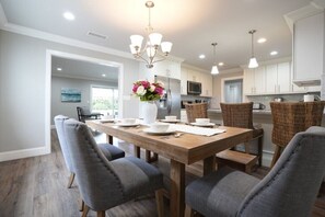 A modern kitchen with white cabinets, a wooden dining table, and grey upholstered chairs.