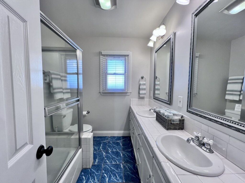 Une salle de bain avec une douche à parois de verre, des toilettes, un lavabo et un grand miroir.