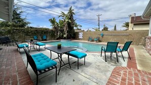 A backyard with a swimming pool, outdoor furniture, and a brick wall. - Stunning 5 Bedroom, 3 Bath Home 1/2 Mile Walk To Disney (Anaheim)