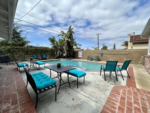 Patio con piscina, mobiliario exterior y pared de ladrillo.