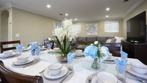 A dining area with a round table set for six, surrounded by chairs. There are decorative vases with flowers on the table. - Stunning 5 Bedroom, 3 Bath Home 1/2 Mile Walk To Disney (Anaheim)