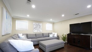 A living room with a sectional sofa, a TV, and artwork on the walls. - Stunning 5 Bedroom, 3 Bath Home 1/2 Mile Walk To Disney (Anaheim)