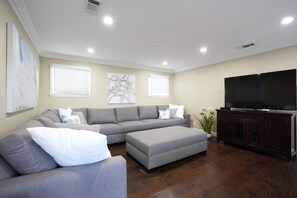 A living room with a sectional sofa, a TV, and artwork on the walls. - Stunning 5 Bedroom, 3 Bath Home 1/2 Mile Walk To Disney (Anaheim)