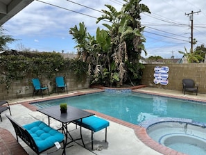 Une piscine avec un jacuzzi, entourée de chaises et d’une table.