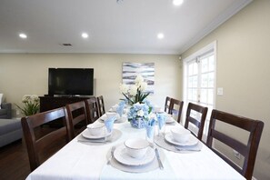 A dining area with a table set for six, a television, and a window with blinds. - Stunning 5 Bedroom, 3 Bath Home 1/2 Mile Walk To Disney (Anaheim)