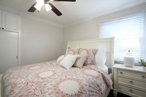 A bedroom with a bed, a nightstand, a ceiling fan, a window with blinds, and a door. - Stunning 5 Bedroom, 3 Bath Home 1/2 Mile Walk To Disney (Anaheim)