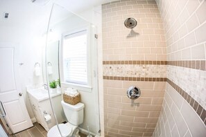 Une salle de bain équipée d’une douche, de toilettes, d’un lavabo et d’une cabine de douche en verre.