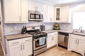 Une cuisine moderne avec des meubles blancs, une cuisinière en acier inoxydable, un four à micro-ondes et un lave-vaisselle.